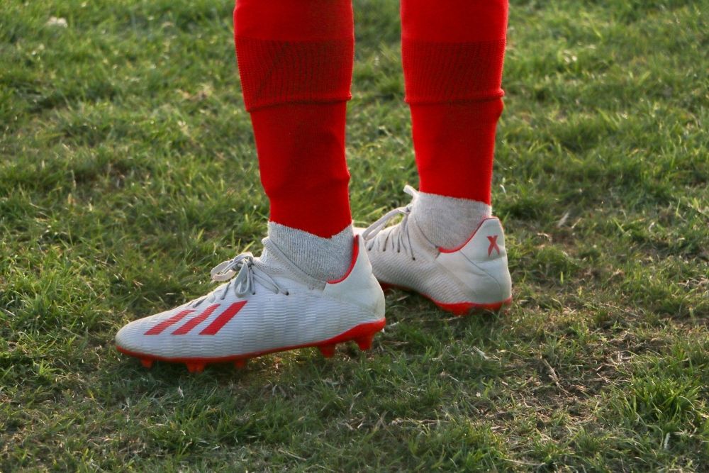 A player is standing on the field with the soccer shoe in his foot