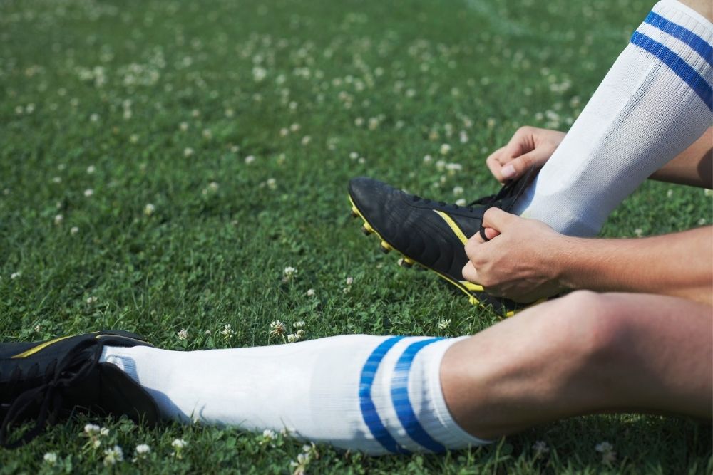A player is tying his soccer shoes