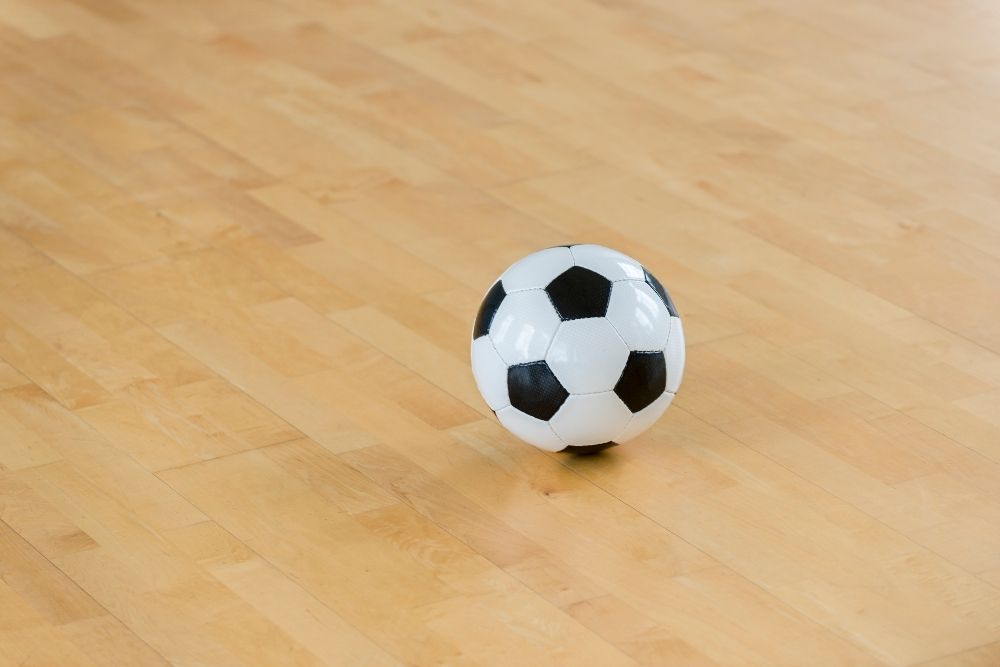 A soccer ball with some white hexagons and black pentagons on the floor