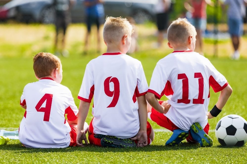 Kid soccer players sit together