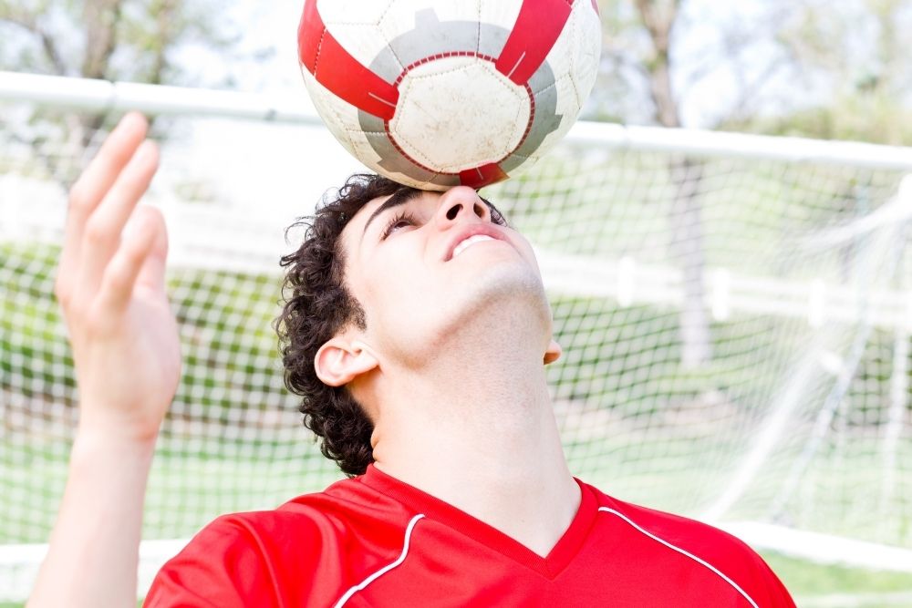 Soccer player hold the ball on his face