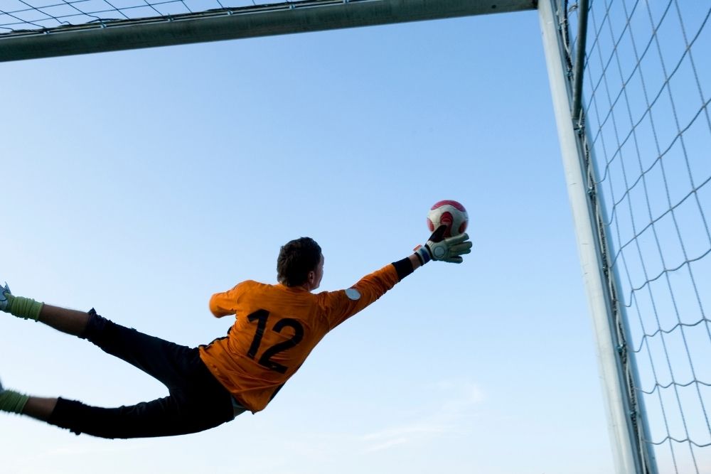 The goalkeeper is flying to save the ball