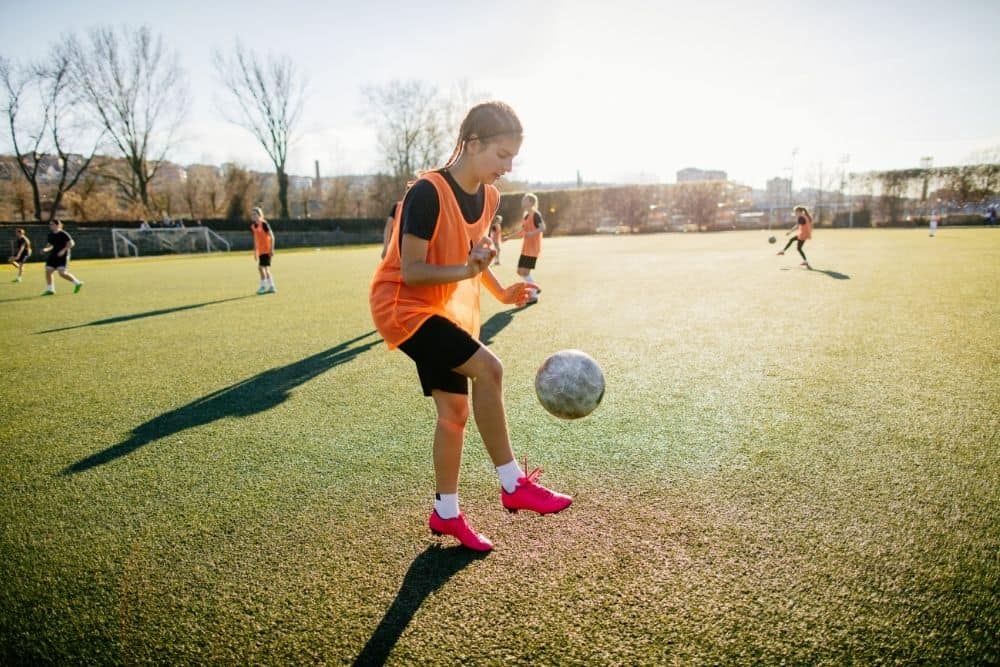 The player is juggling a soccer ball in her training session