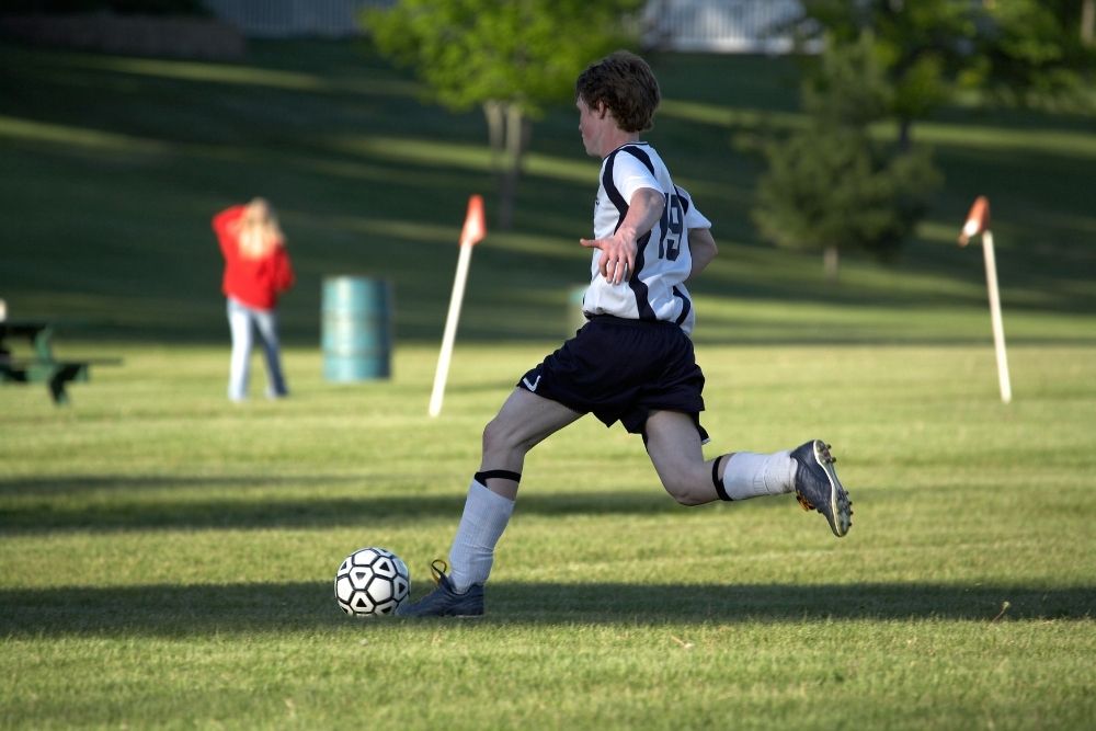 The soccer player is sprinting with a ball