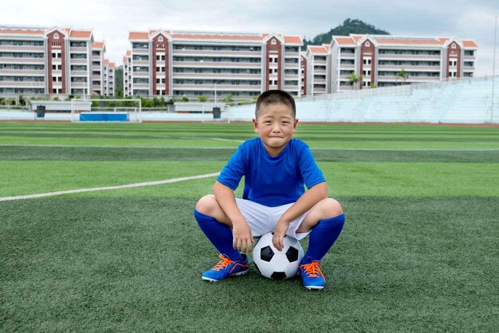 a kid soccer player is sitting on the ball