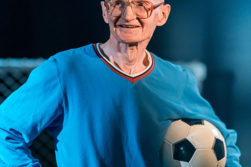 an old soccer player is holding a ball