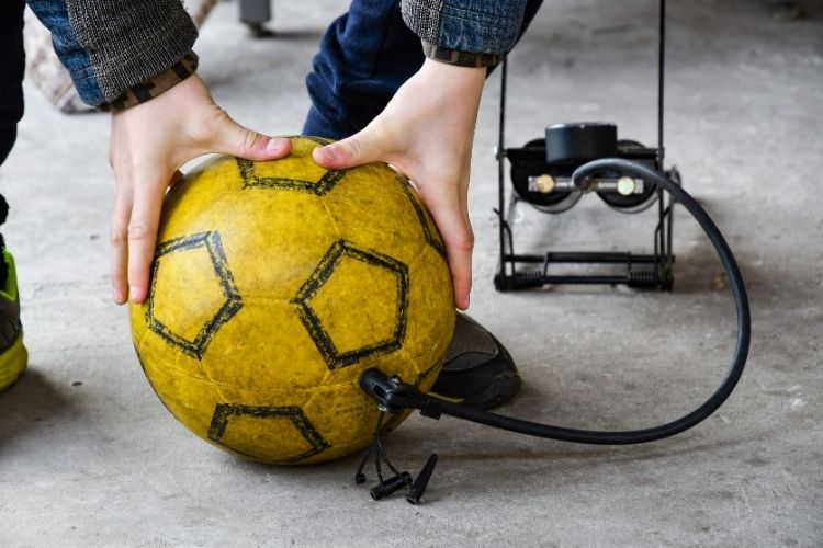 A man inflates for soccer ball.