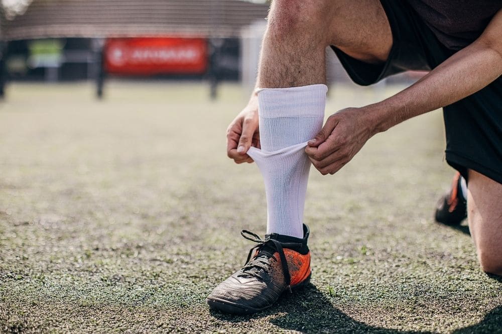 A soccer player is adjusting his socks