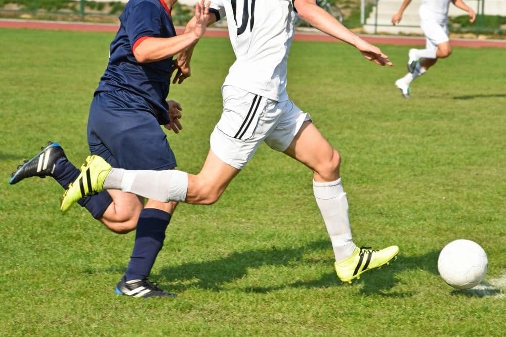 The player in white is running in a soccer match