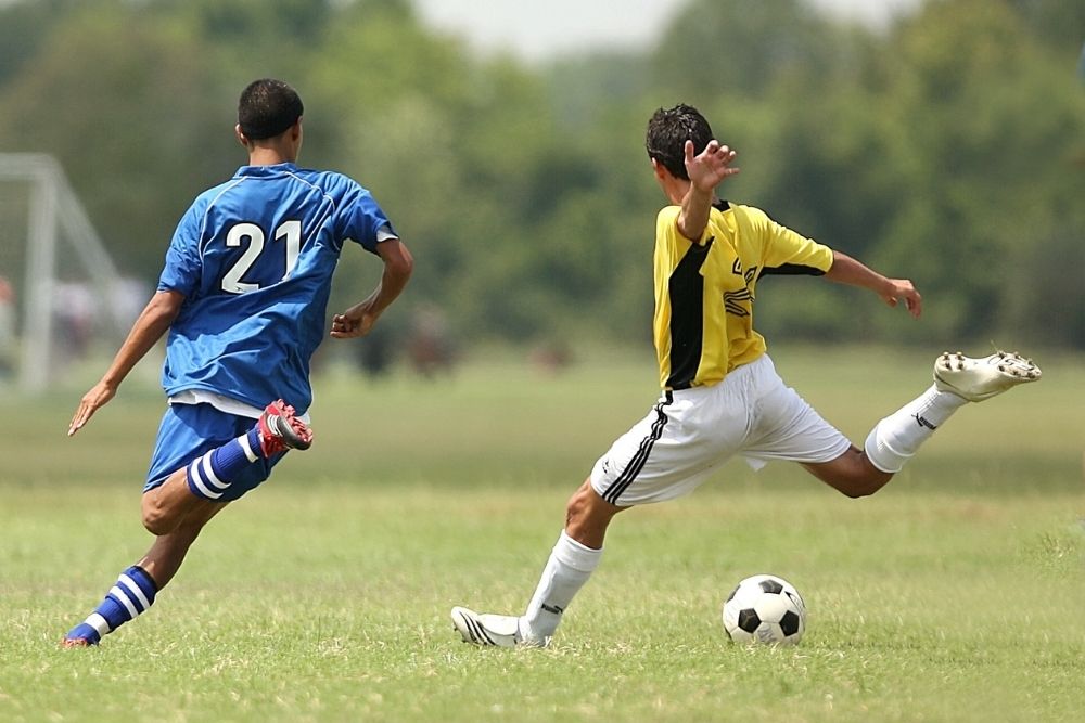 a soccer player in the yellows is kicking the ball