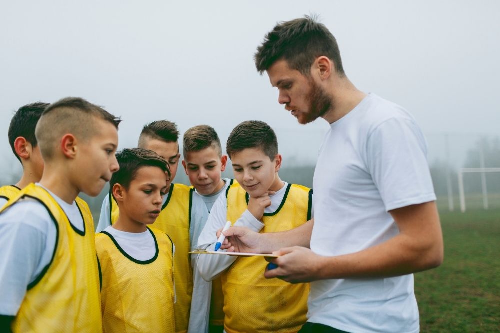 a young soccer coach is giving tactical guidance to the players