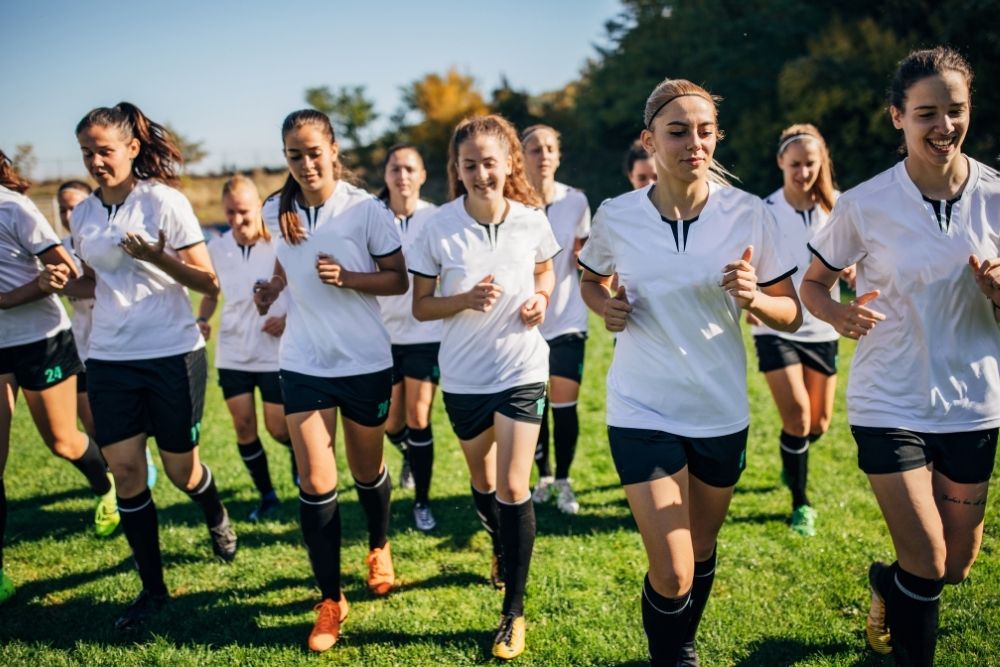 female soccer players jogging for warming up