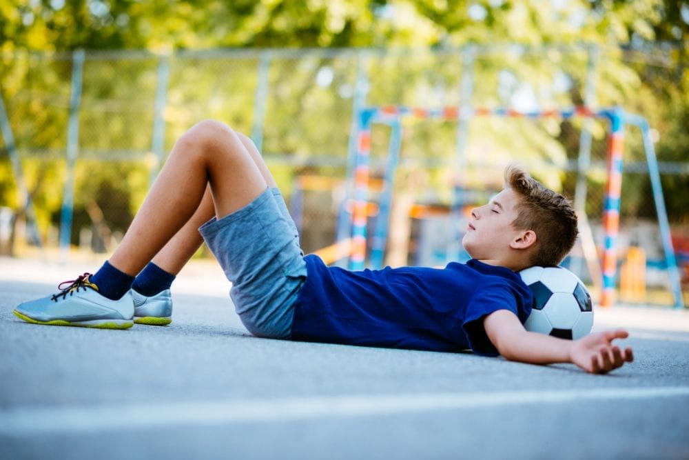 A child soccer player is lying on a ball