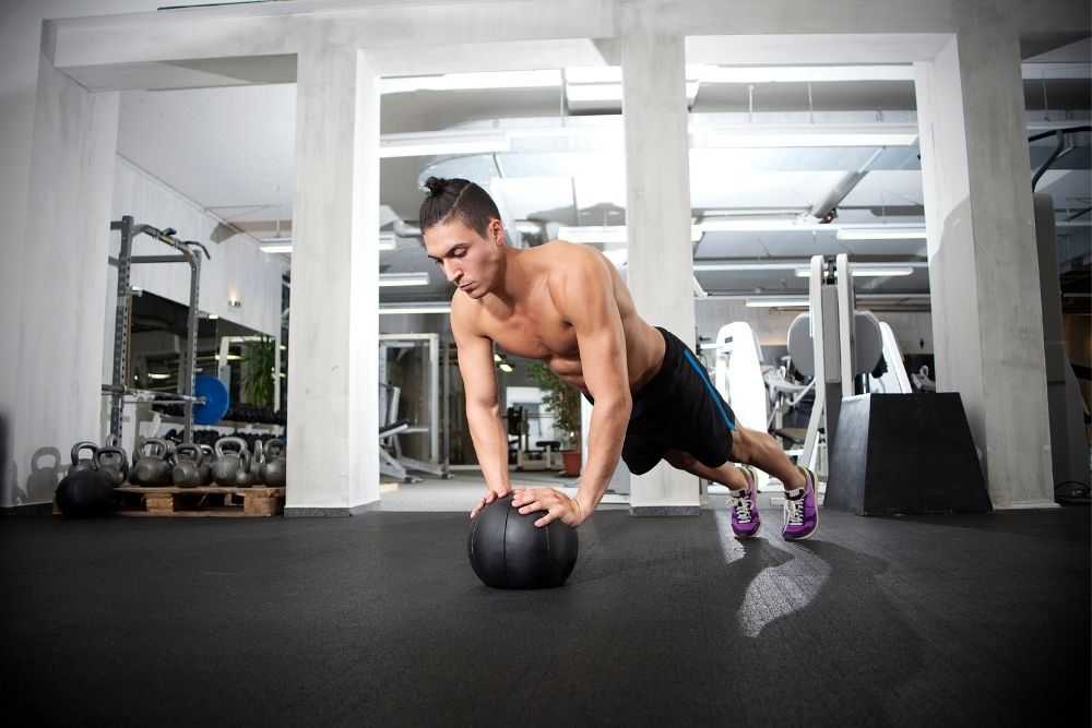 A man is exercising with the medicine ball push-up