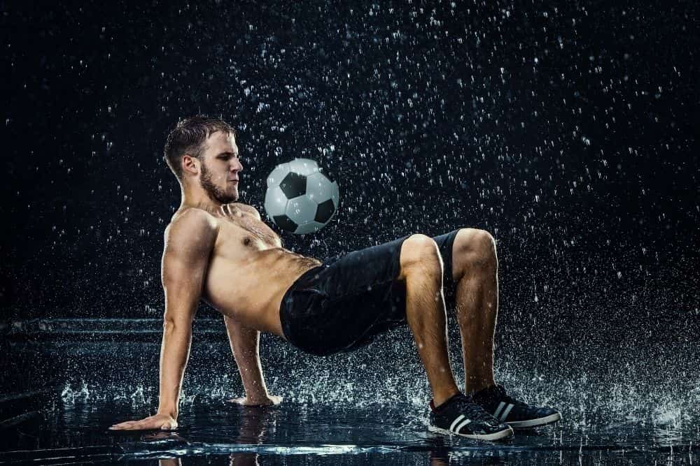 A player is practicing freestyle soccer in the rain