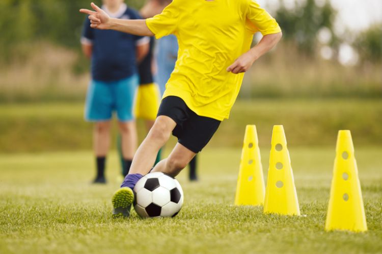 A soccer player is practicing with cones