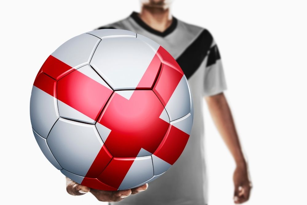 The man is holding a soccer ball with England flag