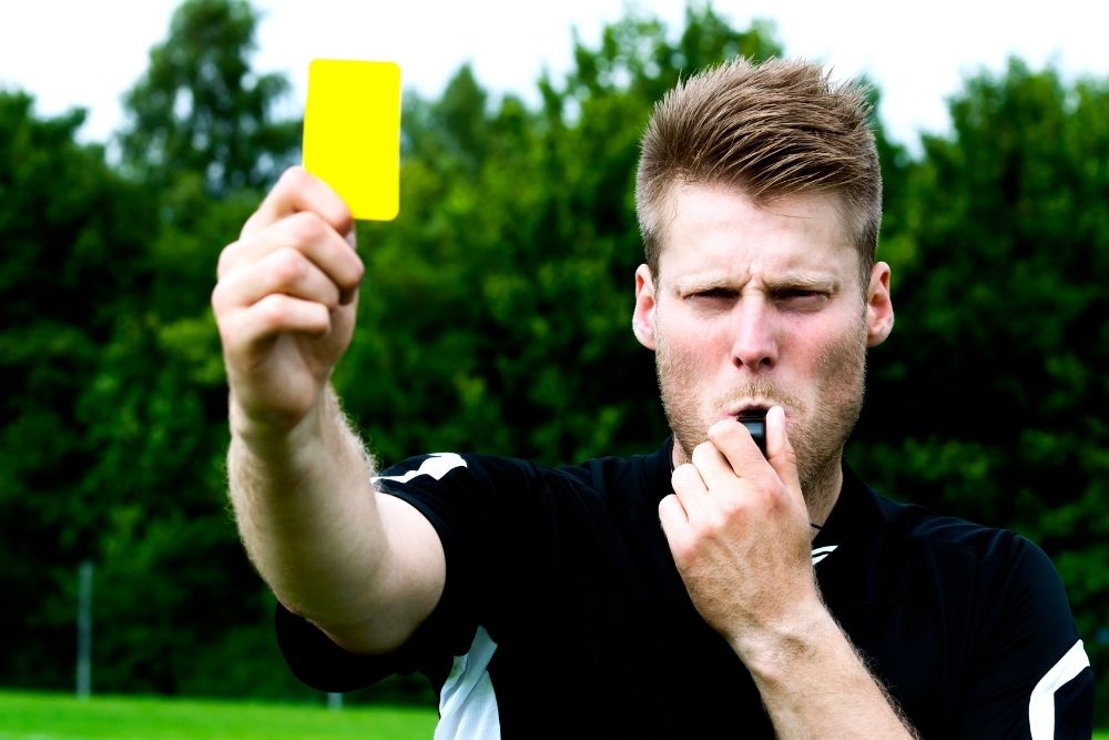 The referee is giving someone a yellow card