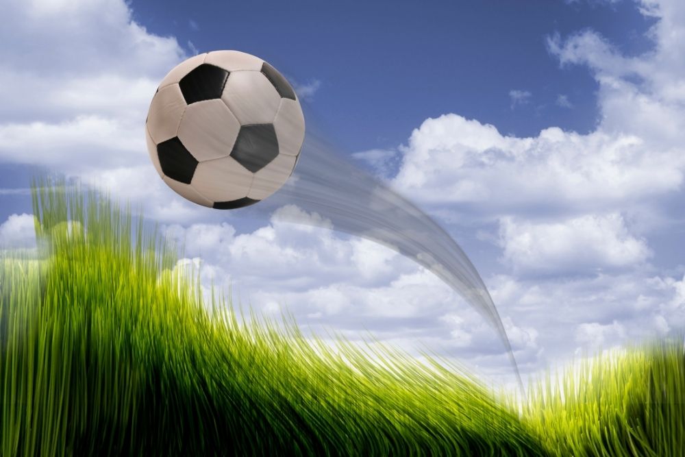 The soccer ball is flying with a curved trajectory