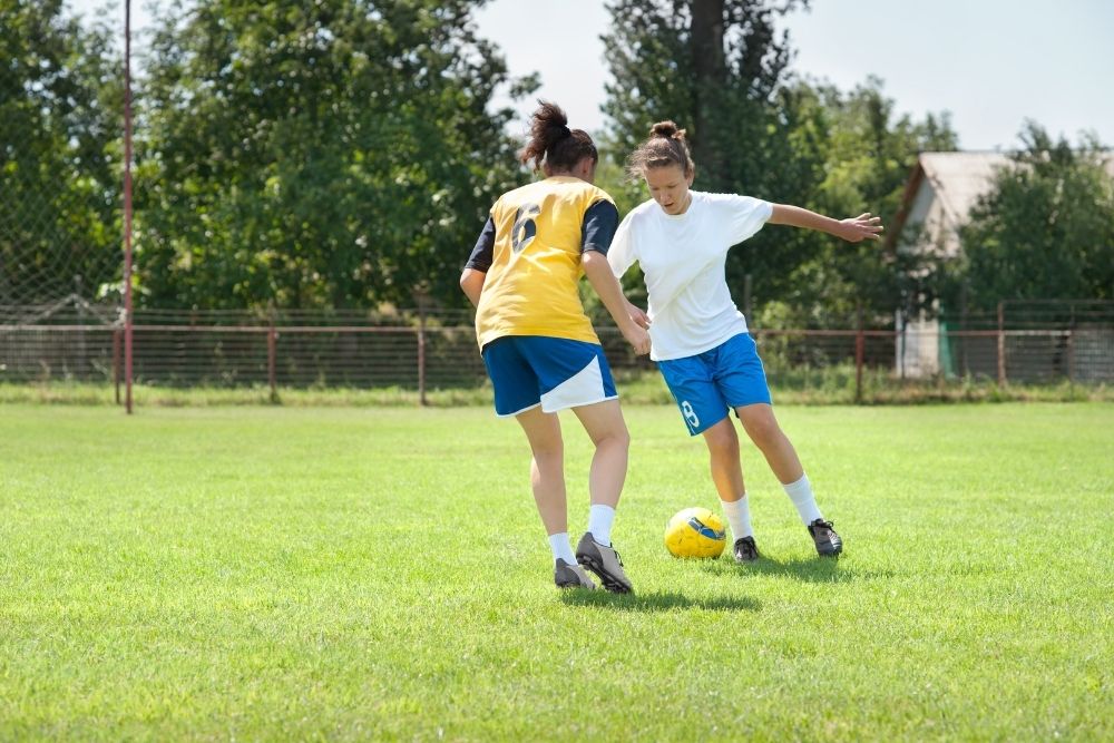 The soccer player is practicing dribble with her teammate