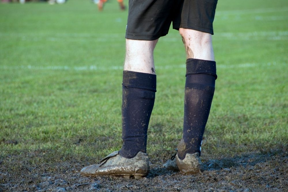 The soccer socks of the player are covered with mud