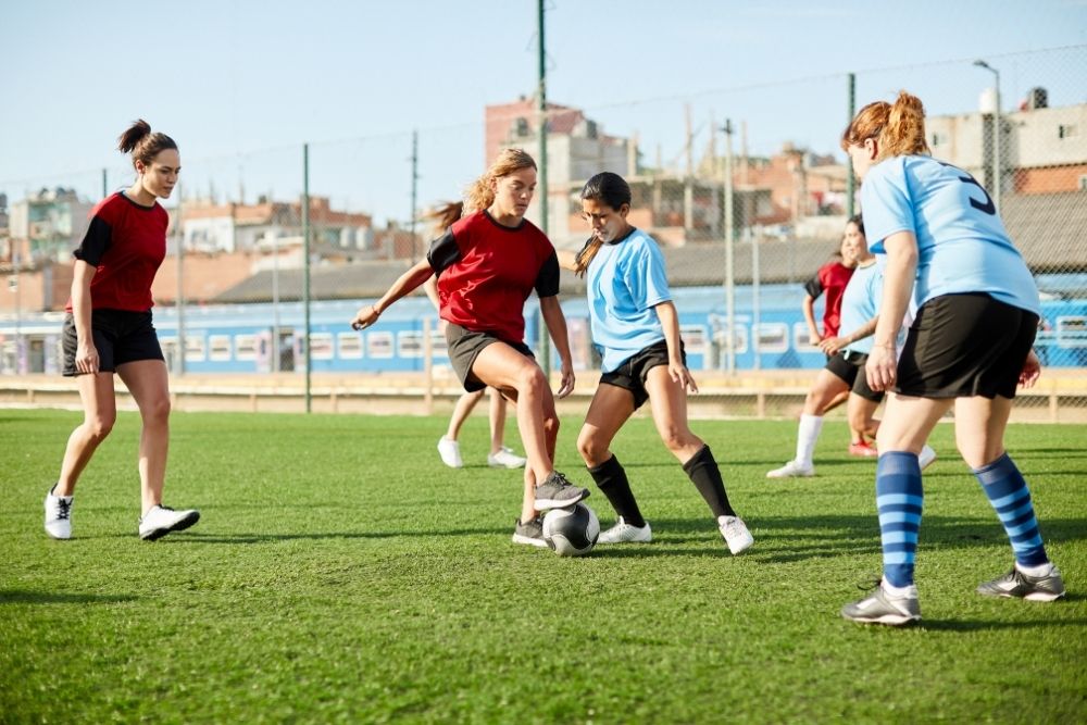 female soccer player dribbling a ball to avoid opponent defenders
