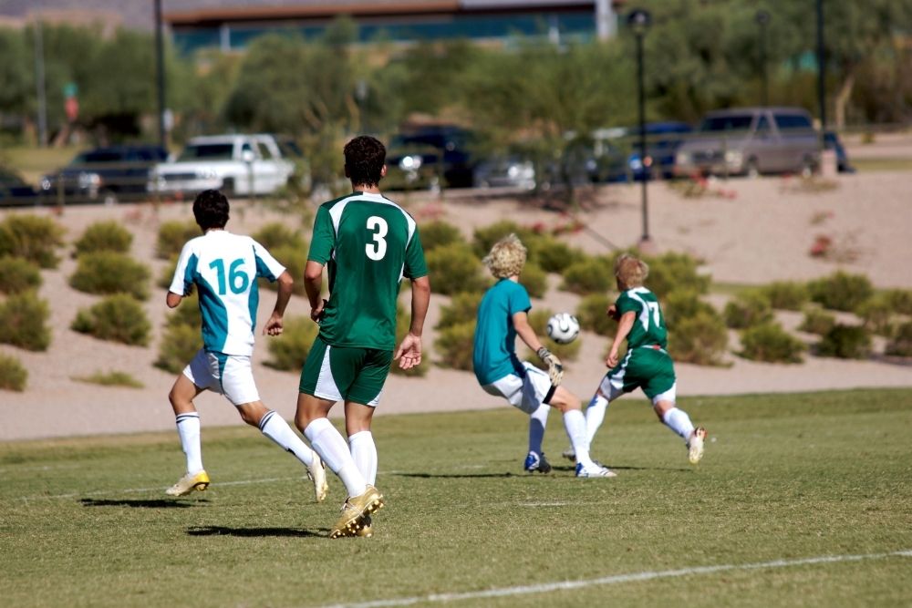 four soccer players chasing a soccer ball