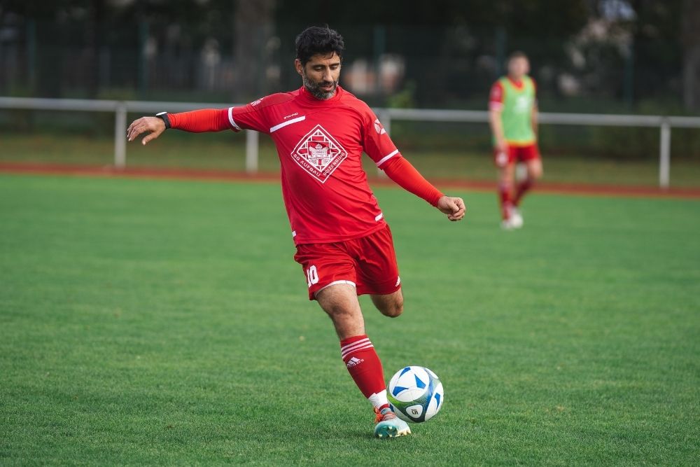 heavy soccer player in red uniform kicking a ball