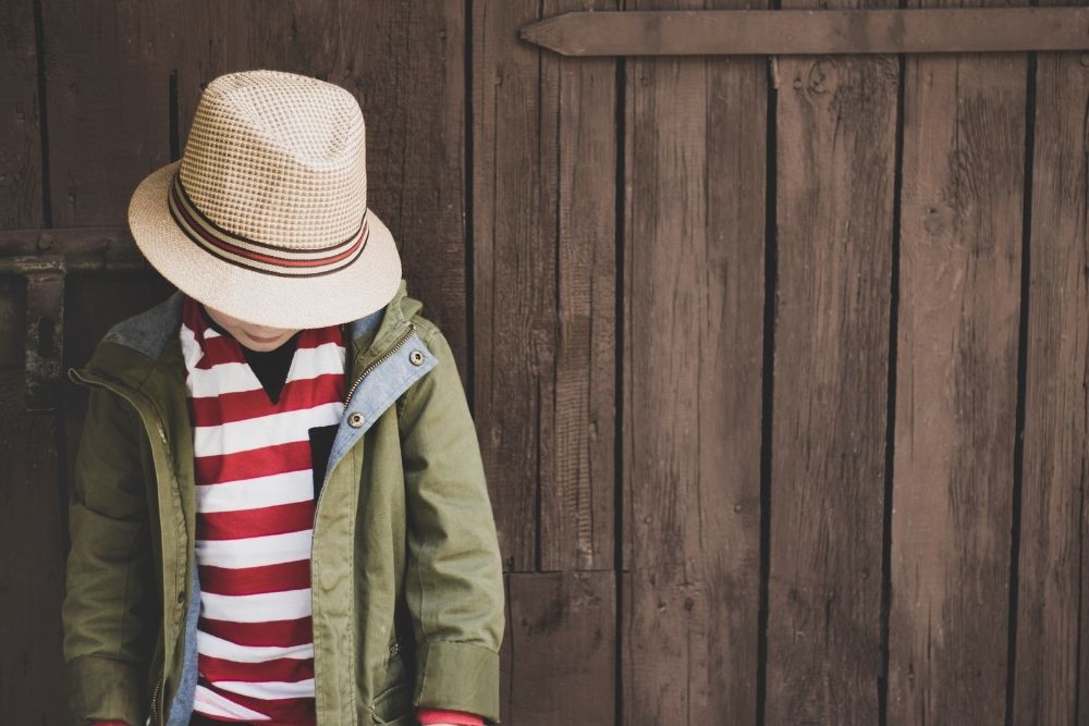 kid wearing brim hat with a white red striped shirt inside a jacket