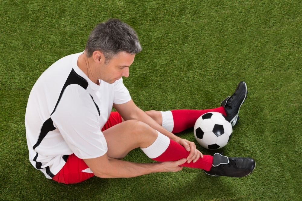 soccer player checking pain in his leg
