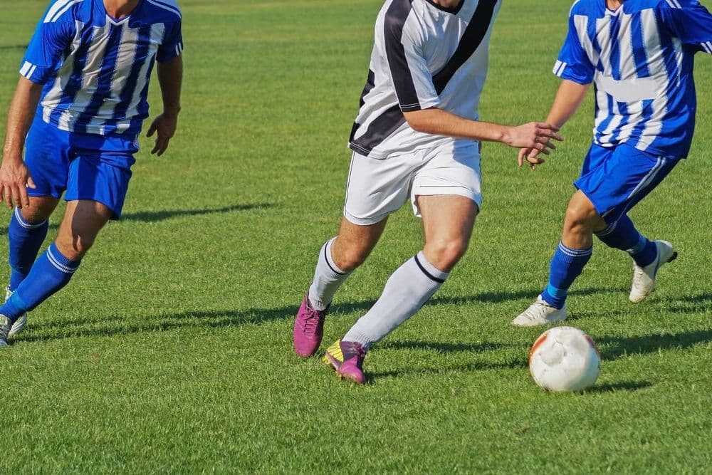 three soccer players in soccer game
