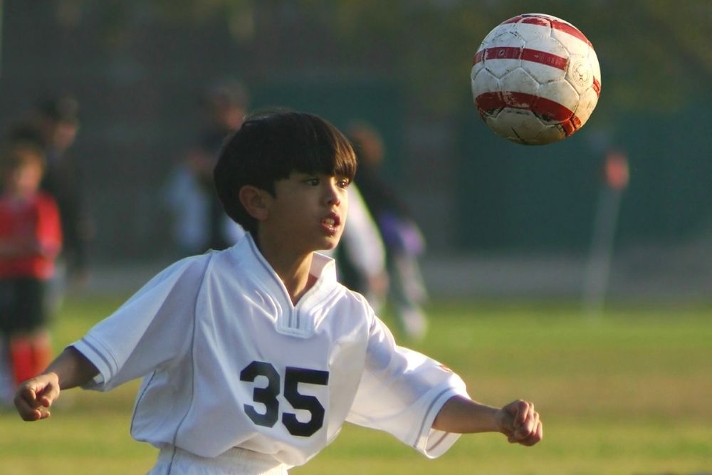 A kid player is preparing for a header