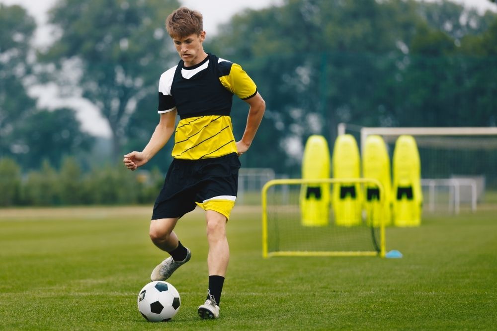 A soccer player is practicing with the ball