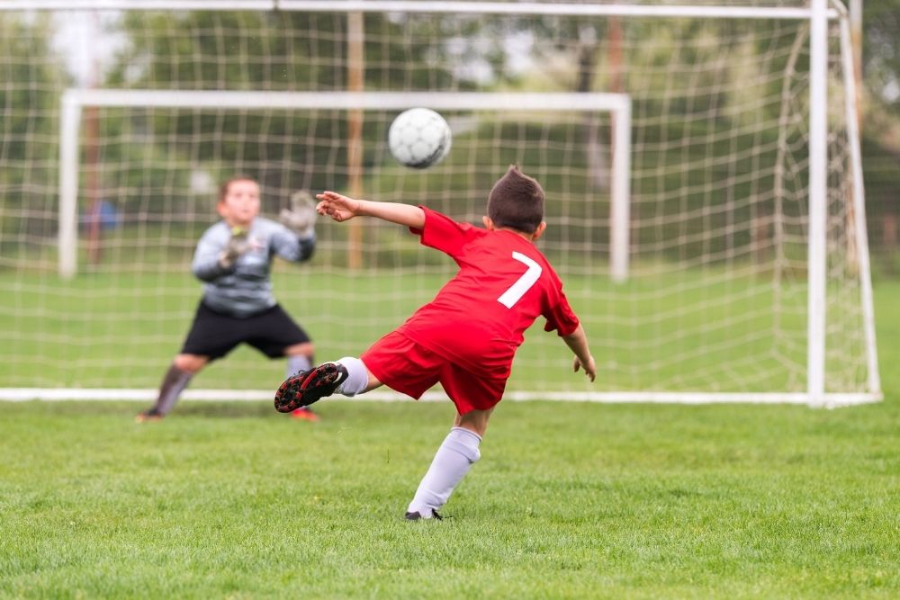 Kid shooting soccer ball to a goal