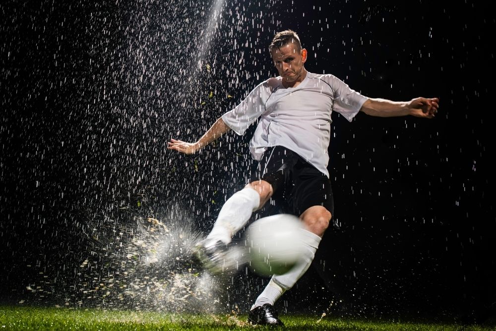 Man shooting soccer ball in the rain