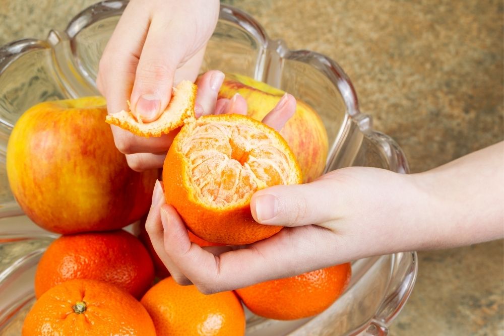 Peeling off orange by hand