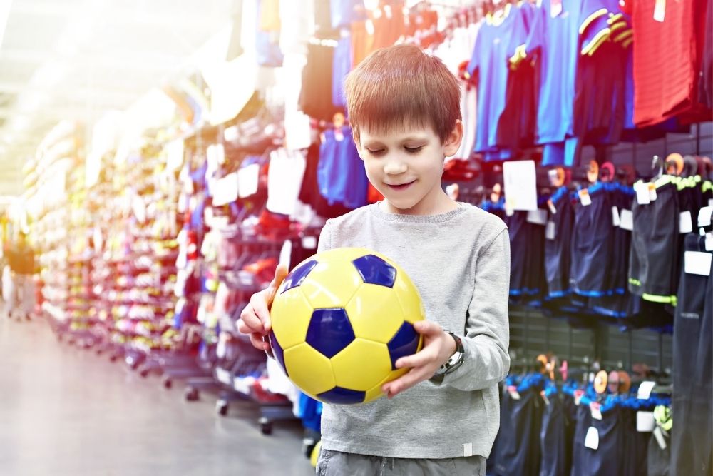 The child at the soccer store is holding a ball