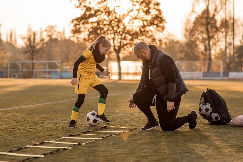 The soccer coach is instructing his young player