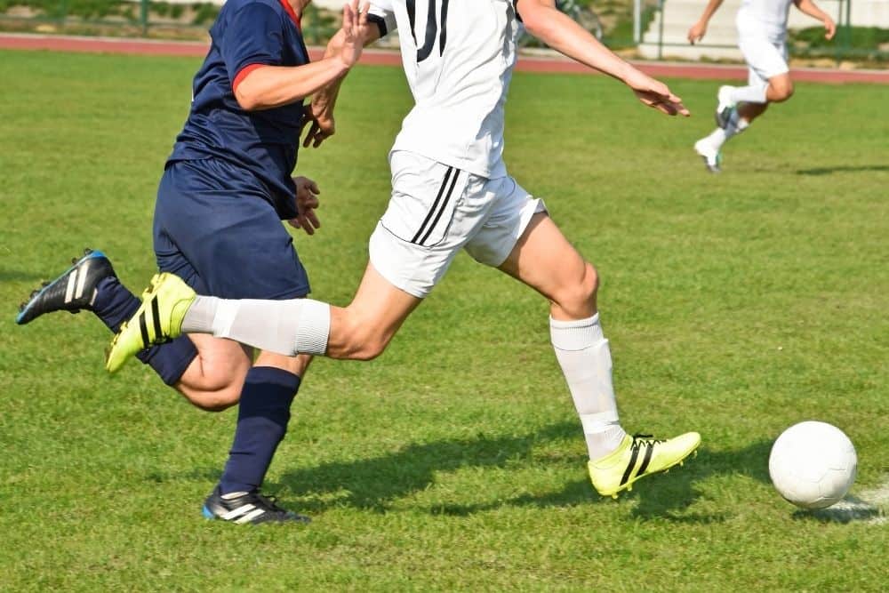 The soccer player is sprinting with the ball