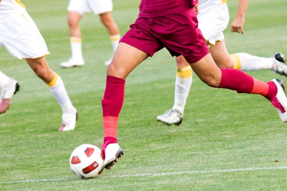 a soccer player is running with the ball in a match