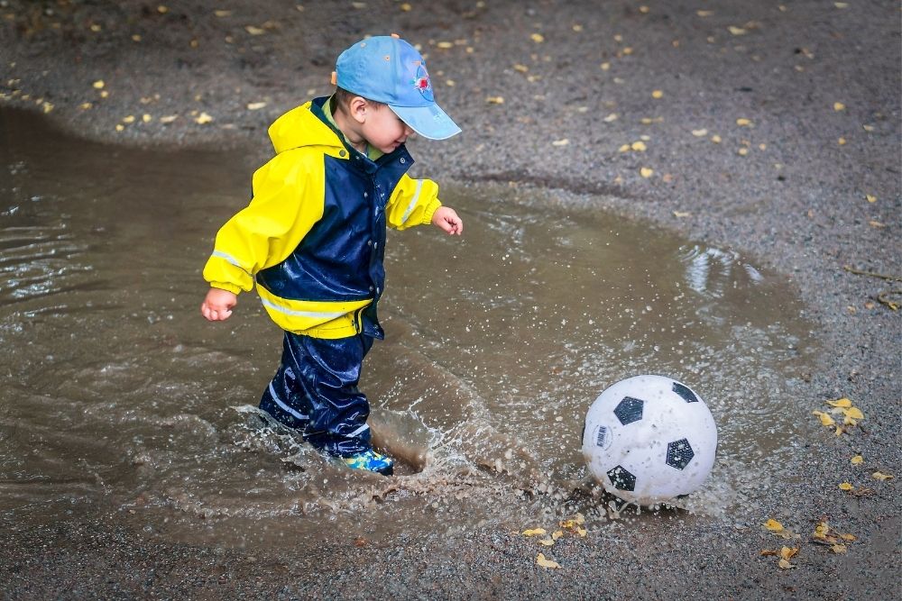 kid playing soccer in the rain