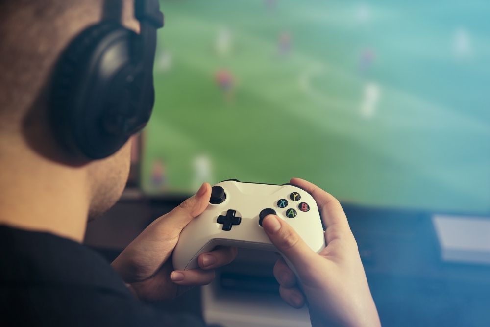 man wearing headphone playing soccer video game with xbox