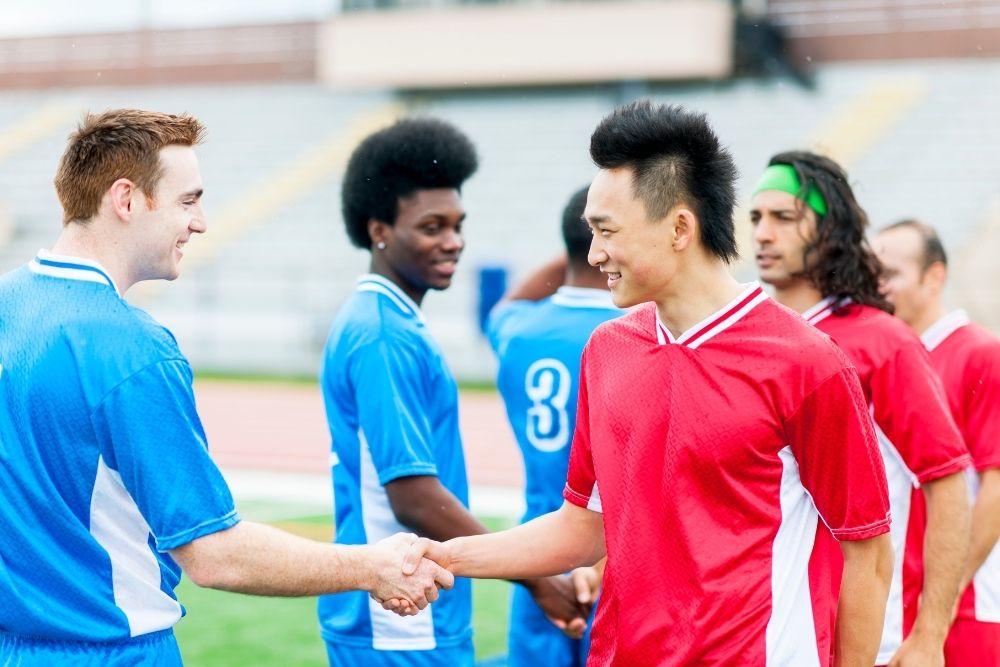 soccer players shaking hand and smiling with their opponent