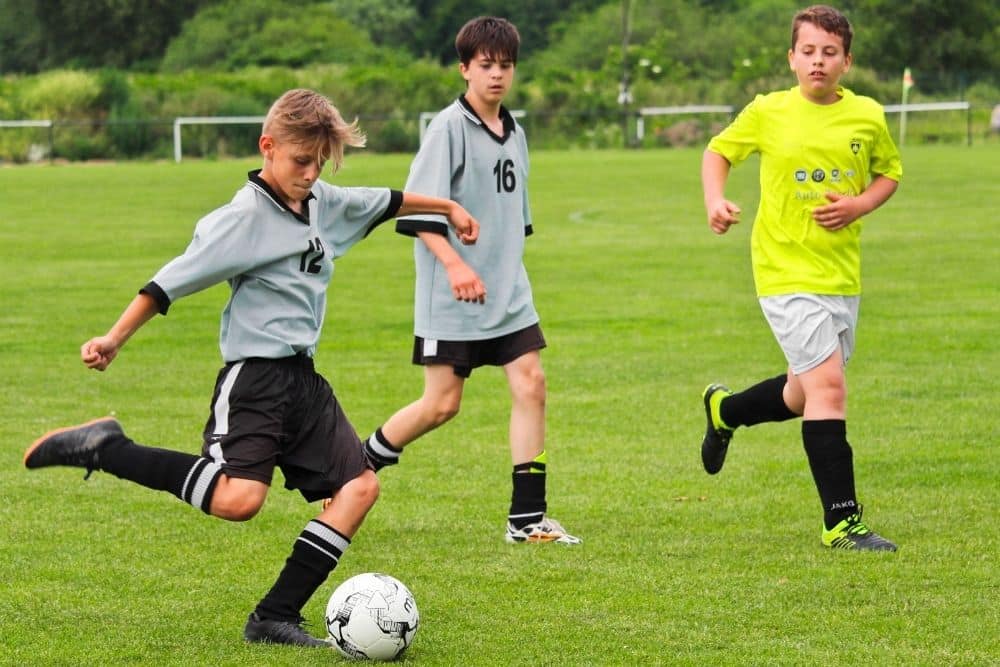 the player is kicking the ball in the young soccer match
