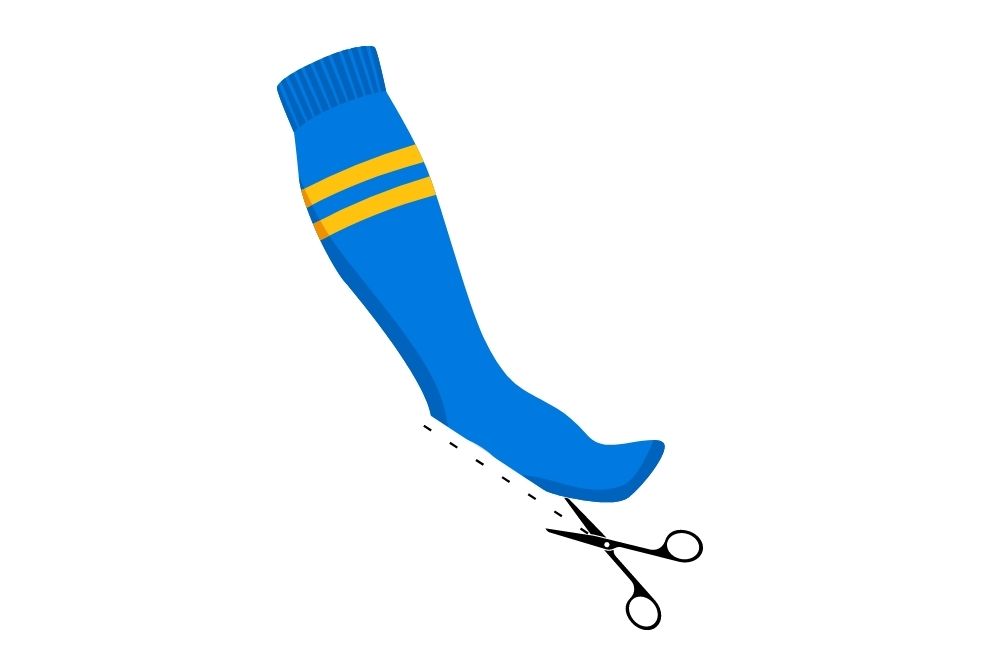 use scissor to cut a blue soccer sock at the heel