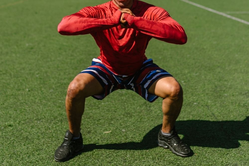 Soccer player squats in the soccer field