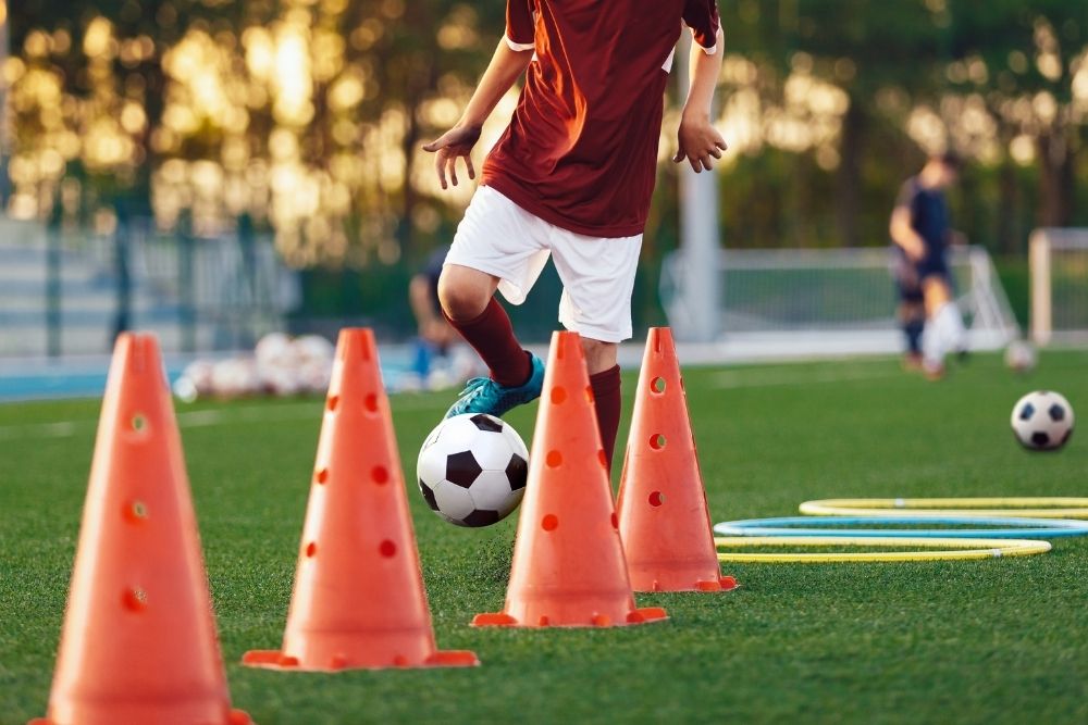 a soccer player practices dribbling cone drills