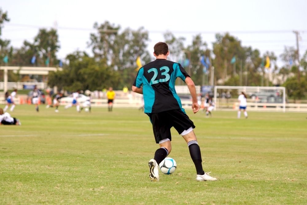 a soccer player wearing 23 soccer jersey and soccer cleats running on the field