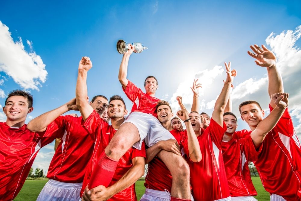 soccer team in red jerseys celebrating