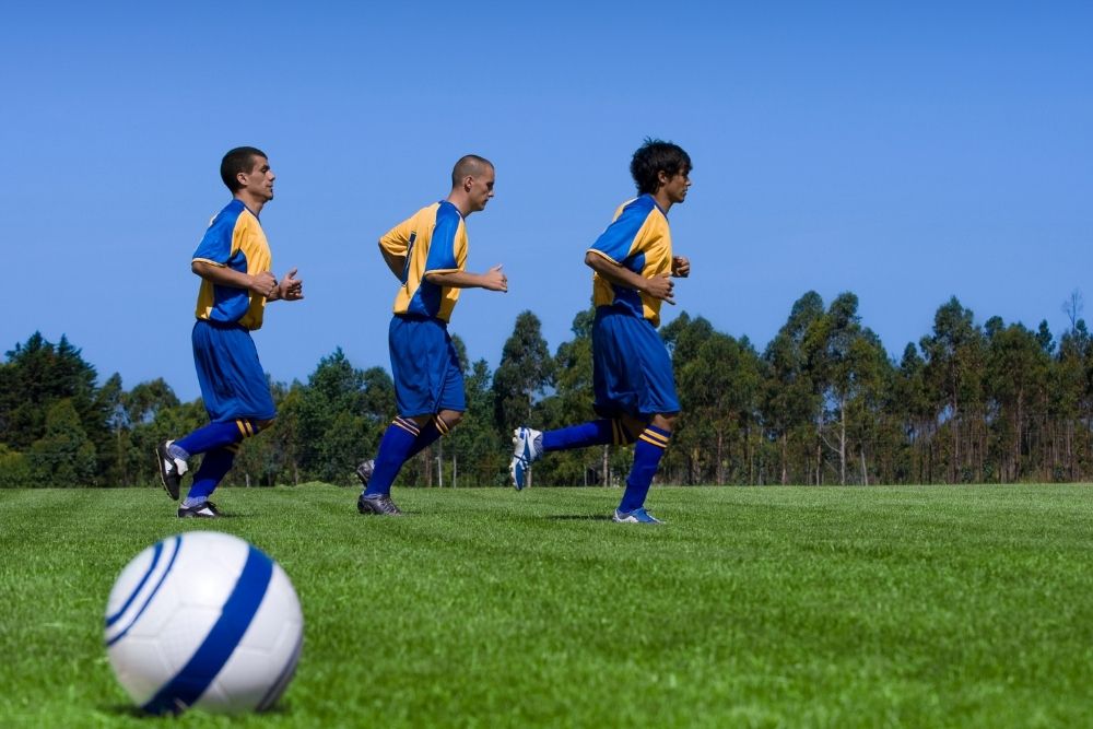 three soccer players warm up before a soccer match